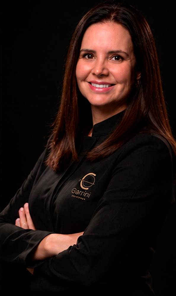 Dra. Ana Garrini, cirurgiã-dentista, de braços cruzados e sorrindo