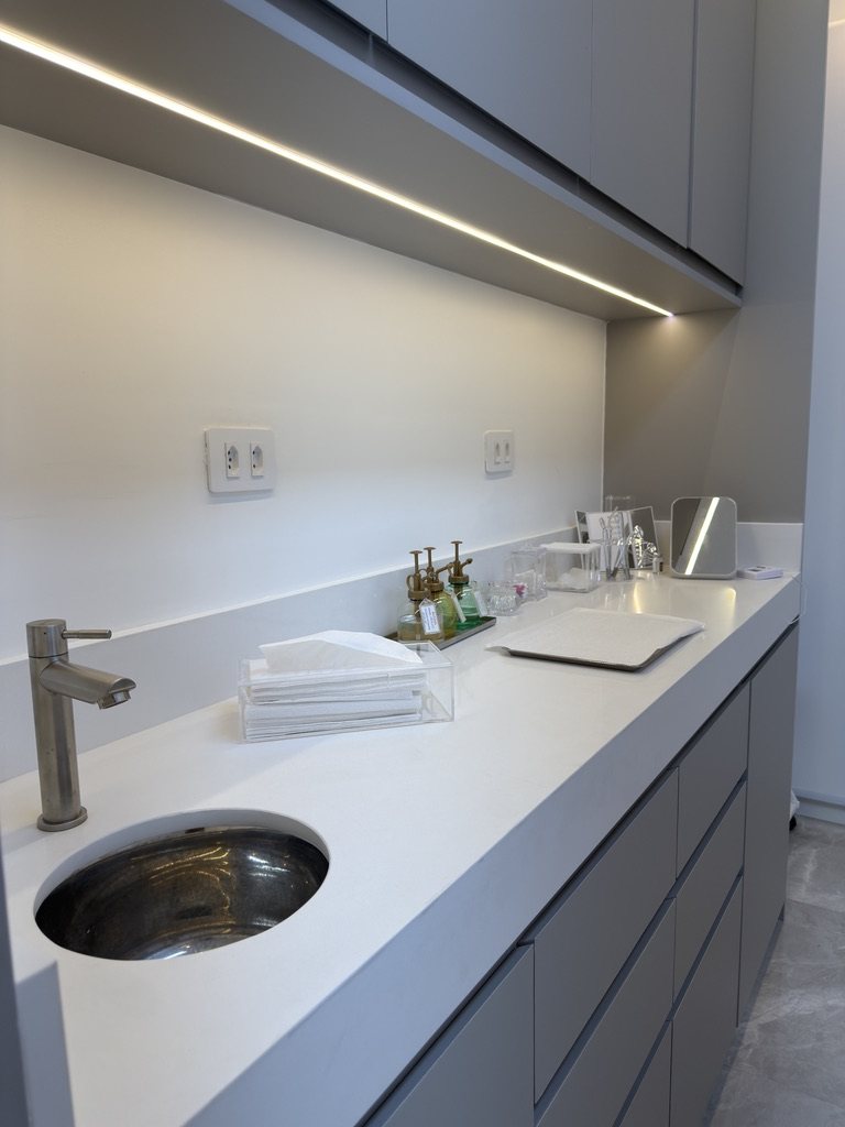 Bancada branca com cuba em inox e iluminação embutida