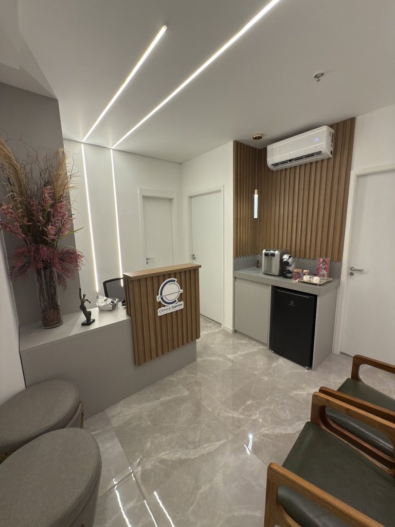 Recepção com balcão em madeira ripada, porcelanato marmorizado e iluminação em linhas de LED